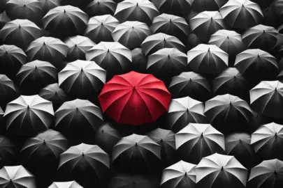 DALL·E 2024 05 26 12.10.43 A black and white depiction of a crowd of umbrellas seen from above. The umbrella in the center is bright red, standing out starkly against the monoch