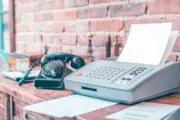 a photo of an old fax machine with a few sheets of TzifQT6eTAODVMMqwQ203A gOTAgEbdRXCVy5Su3nSRlg