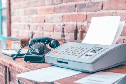 a photo of an old fax machine with a few sheets of TzifQT6eTAODVMMqwQ203A gOTAgEbdRXCVy5Su3nSRlg